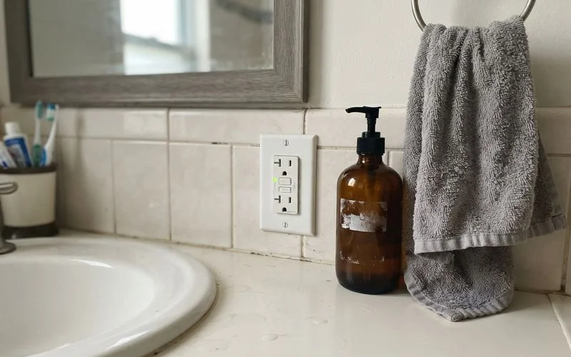 A GFCI outlet with test and reset buttons installed in a bathroom near a sink